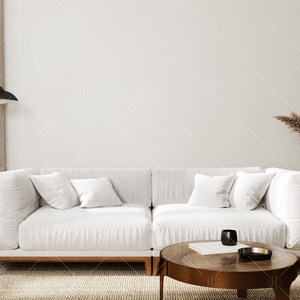 May include: A white sectional sofa with wooden legs sits in a living room with a brown rug, a wooden coffee table, a dried flower arrangement in a white vase, and a black floor lamp.