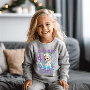 Puede incluir: Una ni&ntilde;a peque&ntilde;a con una sudadera gris y pantalones a juego. La sudadera presenta un gr&aacute;fico de un personaje de dibujos animados, el n&uacute;mero 4 y las palabras "BIRTHDAY GIRL". El dise&ntilde;o incluye copos de nieve y detalles morados.