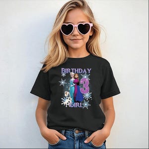 May include: Black t-shirt with a graphic featuring the text "BIRTHDAY GIRL 3" and images of characters from the movie Frozen. The design includes snowflakes and the characters Elsa, Anna, and Olaf.