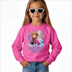 May include: A pink sweatshirt featuring Anna and Elsa from Frozen, with the text "4" and "Birthday Girl". The sweatshirt is long-sleeved and worn by a young girl wearing heart-shaped sunglasses.