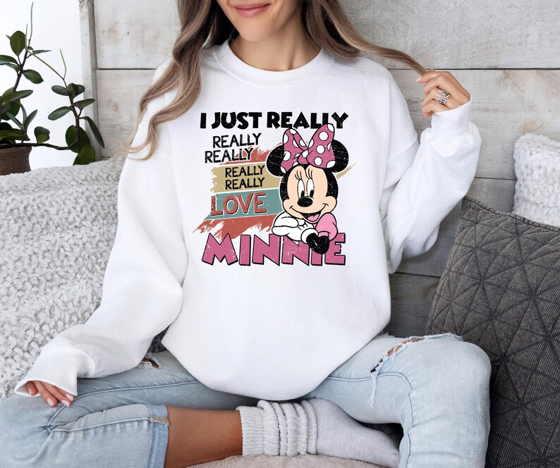 May include: White sweatshirt featuring a graphic of Minnie Mouse with a pink bow and the text "I JUST REALLY REALLY REALLY LOVE MINNIE" in black and pink. The sweatshirt is a casual style.