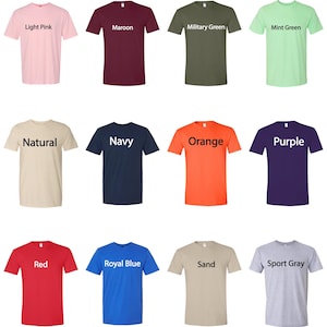 Op de afbeelding: Een verzameling van twaalf T-shirts met korte mouwen in verschillende kleuren, waaronder lichtroze, bordeauxrood, legergroen, mintgroen, naturel, marineblauw, oranje, paars, rood, koningsblauw, zand en sportgrijs. Elke shirt heeft de kleurnaam in het wit gedrukt.