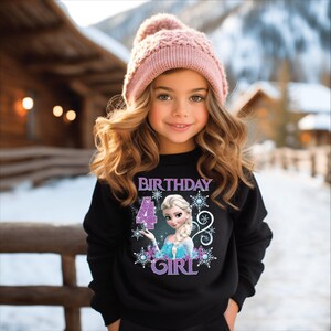 Puede incluir: Una ni&ntilde;a peque&ntilde;a con una sudadera negra con un personaje de dibujos animados y las palabras "BIRTHDAY 4 GIRL". Tambi&eacute;n lleva un gorro de punto rosa. El fondo es una escena invernal nevada.