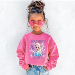 Puede incluir: Una ni&ntilde;a lleva una sudadera rosa con el texto "BIRTHDAY 4 GIRL" y un dibujo animado. Tambi&eacute;n lleva gafas de sol rosas en forma de coraz&oacute;n y vaqueros azules.