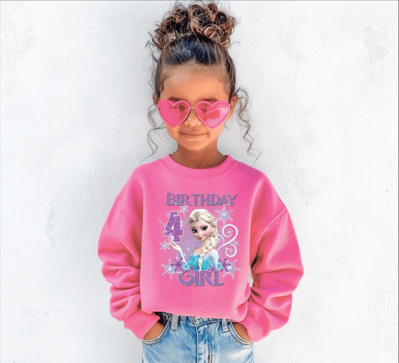 Puede incluir: Una ni&ntilde;a lleva una sudadera rosa con el texto "BIRTHDAY 4 GIRL" y un dibujo animado. Tambi&eacute;n lleva gafas de sol rosas en forma de coraz&oacute;n y vaqueros azules.