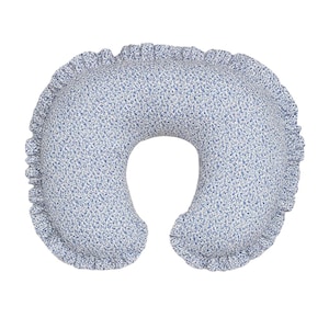 May include: A blue and white floral nursing pillow with a ruffled edge. The pillow has a U-shape design, with a small opening in the center. The fabric has a delicate floral pattern in shades of blue and white.
