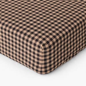 Puede incluir: Primer plano de una tela con estampado de cuadros vichy en color beige y negro. La tela está doblada, mostrando la esquina de una sábana o manta. El patrón es un diseño de cuadros clásico.
