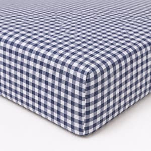May include: A fitted sheet featuring a classic navy blue and white gingham check pattern. The fabric is stretched taut over a rectangular corner, displaying the consistent grid design and the tailored construction of the elasticized edge.