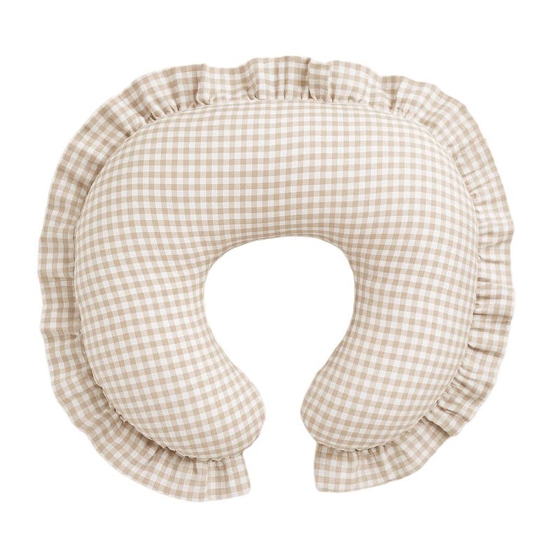 May include: A beige and white gingham nursing pillow with a ruffled edge. The pillow has a crescent shape with a hole in the center, designed for comfortable support during breastfeeding.