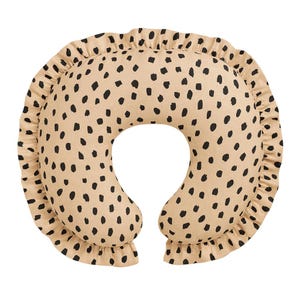 May include: A beige nursing pillow with a black spot pattern and a ruffled edge. The pillow has a U-shape design, providing support for the baby and parent during feeding. The pillow is made of soft fabric.