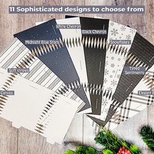 May include: An assortment of 11 sophisticated designs, including "White Canvas", "Soft Stripes", "Midnight Blue Stars", "White Chevron", "Black Chevron", "Snowflakes", "Typed Sentiments", and "Elegant Plaid". The designs are displayed on a wooden surface.