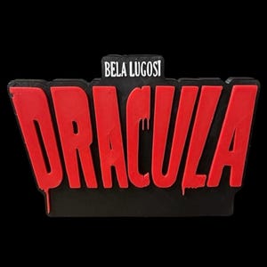 Puede incluir: Un letrero rojo impreso en 3D con las palabras "Dracula" en letras rojas que gotean y "Bela Lugosi" en letras blancas arriba.