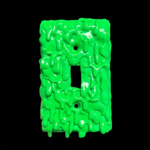 May include: A green light switch cover with a dripping paint effect. The paint is textured and has a glossy finish.