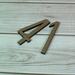May include: Two wooden numbers, 4 and 1, are displayed against a light wood grain background. The numbers are brown with black edges, and the number 4 has a crossbar at the bottom.
