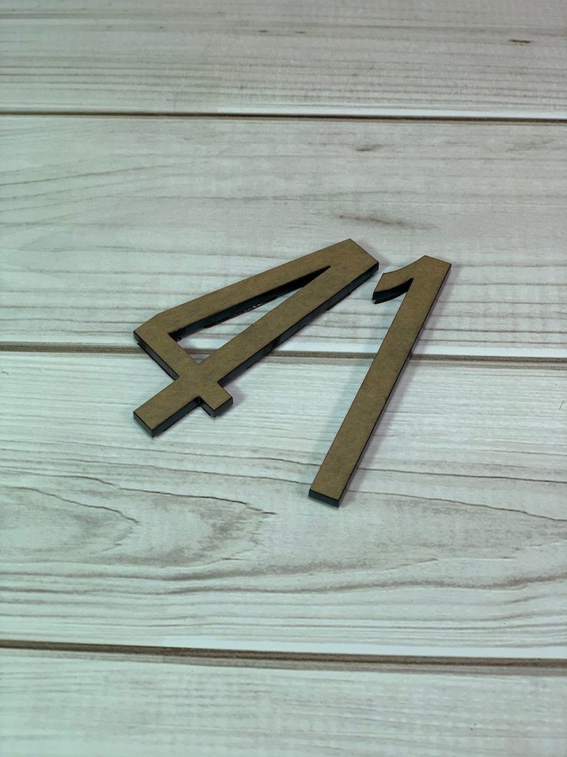 May include: Two wooden numbers, 4 and 1, are displayed against a light wood grain background. The numbers are brown with black edges, and the number 4 has a crossbar at the bottom.