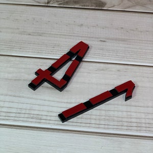 May include: Two wooden number four shapes. The shapes are red with black accents. The shapes are on a light wood grain surface.