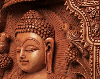 May include: A detailed, wooden carving of Buddha in a meditative pose. The sculpture features intricate details, including a serene facial expression, a bird, and ornate decorative elements. The wood has a warm, brown tone.