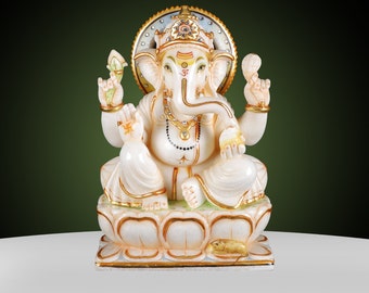May include: A white and gold statue of the Hindu deity Ganesha, seated on a lotus flower. The statue features intricate details, including gold accents, a beaded necklace, and a detailed crown. The background is a gradient of green and white.