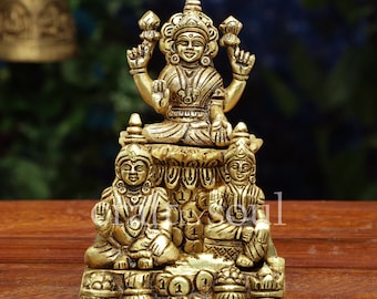 May include: A detailed brass statue of a seated deity with multiple arms, adorned with intricate details. Two smaller figures are seated below the main deity. The statue is on a wooden surface. The logo "craftbysoul" is in the upper right corner.