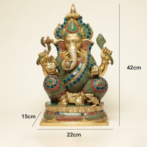 May include: A gold-colored Ganesh statue, 42cm tall, adorned with colorful mosaic-style detailing. The statue features intricate designs with blue, green, and red accents. The base is 22cm wide and 15cm deep. The statue is a representation of the Hindu deity.