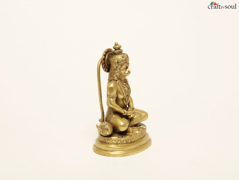 K&ouml;nnte beinhalten: Messingstatue einer sitzenden Gottheit mit aufwendigen Details, darunter eine Krone, Schmuck und eine Keule. Die Figur befindet sich in einer meditativen Pose, die H&auml;nde ruhen im Scho&szlig;. Die Statue steht auf einem kreisf&ouml;rmigen Sockel.