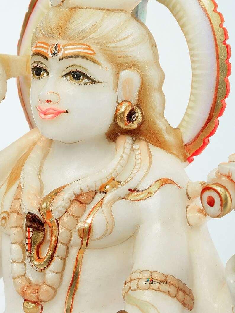 May include: A detailed, close-up of a white marble statue of a deity with intricate gold and red accents. The statue features detailed facial features, jewelry, and a halo. The overall theme is religious art.
