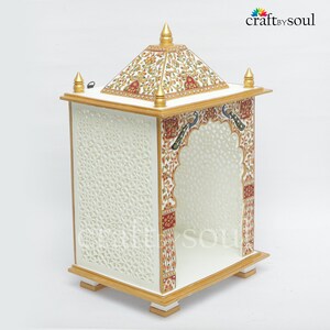 以下が含まれることがあります： 白木の寺院で、側面に複雑な切り絵模様があり、アーチ型の開口部があります。 金色のアクセントがあり、赤、緑、黄色の花柄と孔雀のモチーフで飾られています。 上部はピラミッド型です。