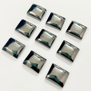May include: Ten black square-shaped gemstone cabochons with a smooth, polished surface.