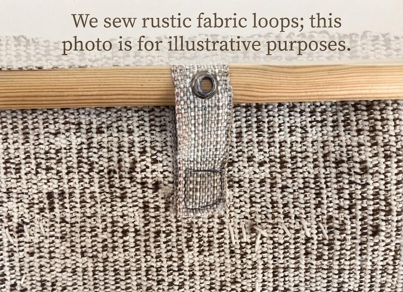 Op de afbeelding: Een gestructureerd beige en bruin geweven stoffen paneel met een lichtgekleurde houten roede door een stoffen lus met een metalen oogje. De tekst "We sew rustic fabric loops; this photo is for illustrative purposes." is zichtbaar.