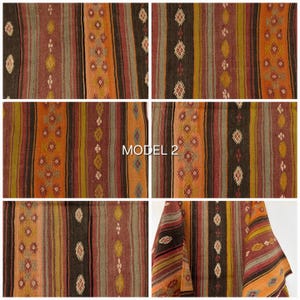 Op de afbeelding: Een textielstof met verticale strepen in tinten bruin, oranje, olijfgroen en gedempt rood. Het patroon bevat herhalende ruitvormige motieven in wit, geel en rood. De tekst "MODEL 2" is in het midden van de afbeelding gedrukt.