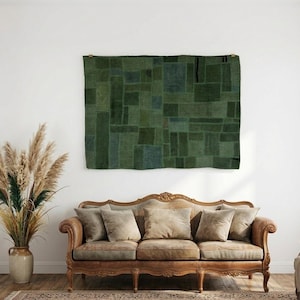 Puede incluir: Un tapiz de pared rectangular que presenta un diseño de patchwork en varios tonos de verde oscuro. El tejido está compuesto por múltiples segmentos rectangulares cosidos entre sí, creando un patrón de cuadrícula geométrica en toda la superficie.