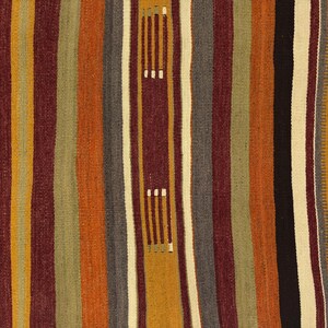 May include: A woven textile featuring vertical stripes in shades of burnt orange, deep maroon, olive green, mustard yellow, charcoal gray, and cream. The fabric displays a repeating pattern of small, light-colored rectangular stitch accents.