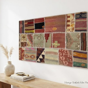 Könnte beinhalten: Ein rechteckiger Wandbehang aus Vintage-türkischem Kelim-Patchwork mit verschiedenen gewebten Stoffquadraten in Rot-, Grün-, Braun- und Gelbtönen, die durch sichtbare weiße Nähte verbunden sind. Das Stück misst 125 mal 71 Zentimeter.
