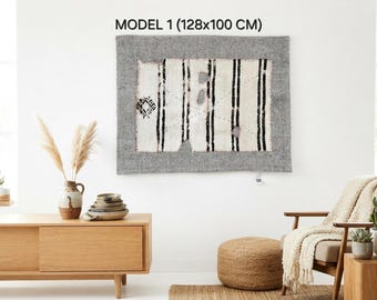 May include: A rectangular wall hanging labeled MODEL 1 (128x100 CM) featuring a central white panel with vertical black stripes and small geometric motifs, framed by a wide, textured gray border with visible stitching along the edges.