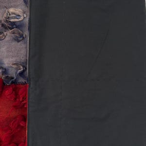 May include: A textile artwork featuring a patchwork design. The left side showcases a blend of textures and colors, including red, orange, gray, and blue. The right side is a solid black fabric. The piece is likely a wall hanging or decorative textile.