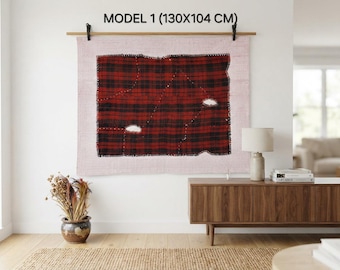 May include: A rectangular wall hanging labeled MODEL 1 (130X104 CM) featuring a light pink fabric background with a central red and black plaid patch. The patch has visible black stitched edges and two small white frayed holes on the surface.
