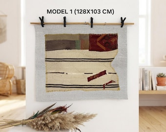 May include: A rectangular wall hanging measuring 128x103 cm, labeled MODEL 1. It features a light gray fabric base with a central patchwork design of cream, dark brown, and red patterned textile segments, accented by horizontal black stripes.