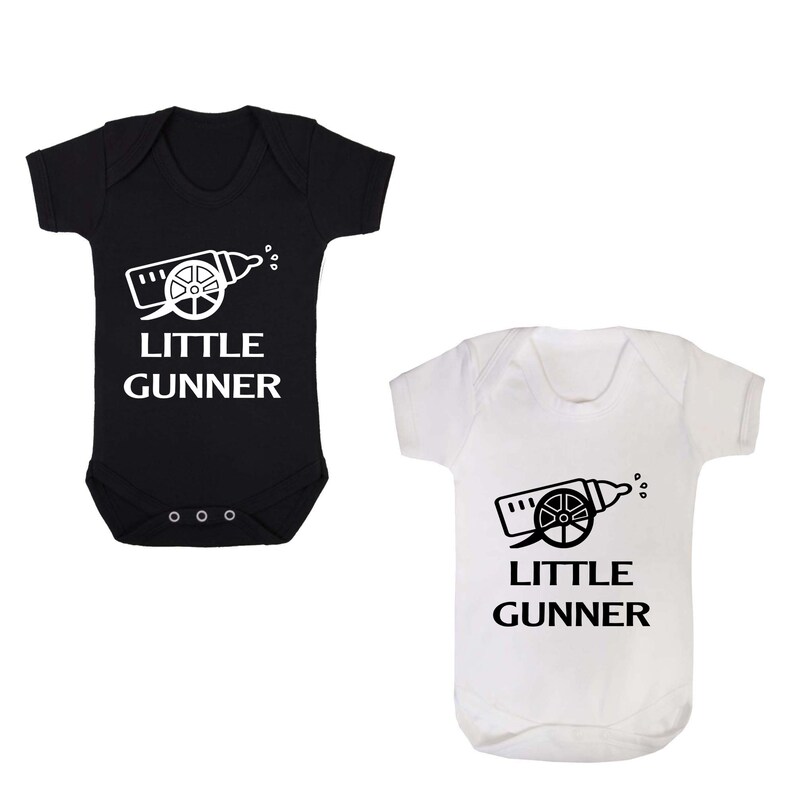 May include: Two baby onesies, one black and one white, with a white graphic of a baby bottle shaped like a cannon with the text "Little Gunner" underneath.