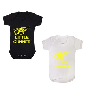 May include: Two baby onesies, one black and one white, with a yellow graphic of a baby bottle shaped like a cannon and the text "Little Gunner".