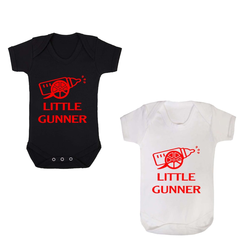 May include: Two baby onesies, one black and one white, with a red graphic of a baby bottle shaped like a cannon with the text "LITTLE GUNNER" underneath.
