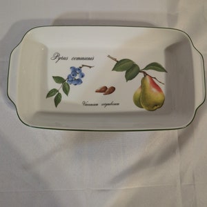 May include: White rectangular baking dish with a green rim. The dish has a botanical illustration of a pear, blueberries, and almonds with the text "Pyrus communis" and "Vaccinium corymbosum" printed on the bottom.