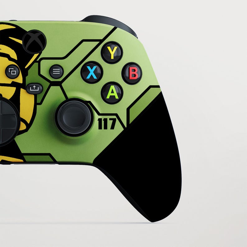 May include: A custom video game controller in green and black. The controller has a unique design with the number "117" and coloured buttons: Y (yellow), X (blue), B (red), and A (green). The controller has a black D-pad and analogue sticks.