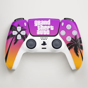 Pode incluir: Um comando de videojogos branco com um design degradé em roxo, rosa e laranja com silhuetas de palmeiras pretas nas pegas. O painel tátil central apresenta o texto branco Grand Theft Auto e o comando inclui botões padrão.