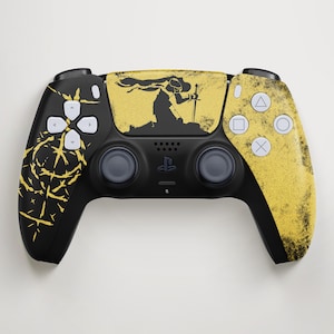 Pode incluir: Controlo PlayStation 5 preto e dourado. O controlo apresenta um design dourado no touchpad e no lado direito, com uma silhueta preta de uma figura segurando uma espada. O lado esquerdo tem um design abstrato dourado.