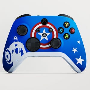 Può includere: Controller Xbox blu e bianco con tema Captain America. Il controller ha uno sfondo blu con stelle bianche e un design a scudo di Captain America. I pulsanti sono colorati e una silhouette bianca di Captain America è a sinistra.