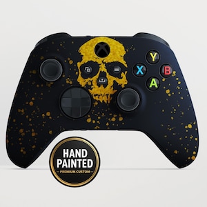 Può includere: Controller Xbox nero con un design a teschio dorato dipinto a mano e spruzzi dorati. Il controller ha pulsanti colorati e un adesivo circolare con la scritta "HAND PAINTED - PREMIUM CUSTOM".