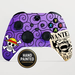 以下が含まれることがあります： 紫色の背景に黒い渦巻き模様が施された、手描きのXboxコントローラー。 黄色の帽子をかぶったドクロマークと「WANTED」ポスターのデザインが特徴です。 「HAND PAINTED - PREMIUM CUSTOM」の文字も表示されています。
