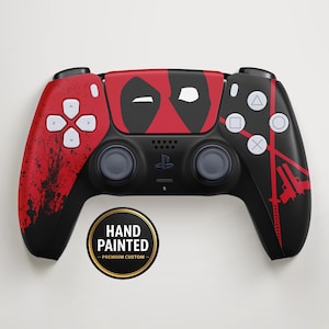 Könnte beinhalten: Ein handbemalter schwarz-roter Gamecontroller mit Deadpool-Design. Der Controller hat eine rote Oberseite mit der Deadpool-Maske und roten Akzenten an den Seiten. Die Knöpfe sind weiß. Der Controller hat den Text "HAND PAINTED - PREMIUM CUSTOM" auf einem runden Aufkleber.