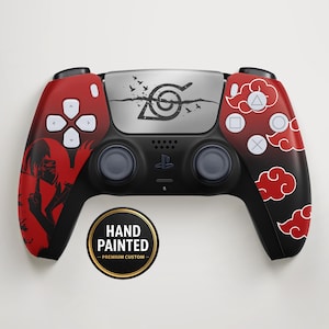 Può includere: Controller PlayStation 5 personalizzato dipinto a mano. Il controller presenta un design rosso e nero con un'illustrazione di personaggi e un motivo a nuvole. Il centro ha un pannello argentato con un simbolo e testo. Pulsanti bianchi e joystick neri.