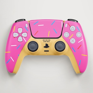 Può includere: Un controller per videogiochi wireless con una scocca superiore rosa decorata con granelli bianchi, blu, gialli e rossi sparsi. La parte inferiore del controller è di colore beige tinta unita, con levette analogiche nere e tasti bianchi.